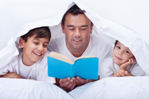 Father reading a story to his little sons - family time together