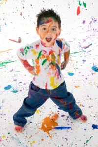Adorable 3 year old boy covered in bright paint.