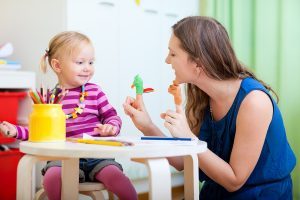 Young mother and her toddler girl playing together with finger toys